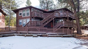 Une cabane à plusieurs étages, avec une façade en bois, un balcon et un escalier menant aux niveaux supérieurs.