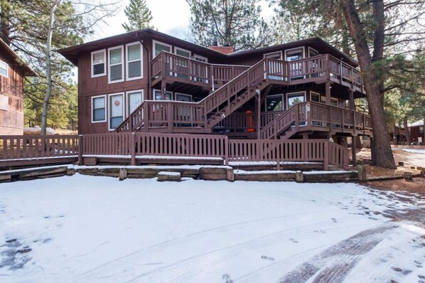 A multi-story cabin with a wooden exterior, a balcony, and a staircase leading to the upper levels. - Updated 2-bedroom condo in Angel Fire 1 BLOCK FROM LIFTS (Angel Fire)
