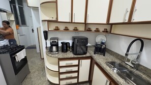 Eine kleine Küche mit Gaskochfeld, Kaffeemaschine, Toaster und Spüle.