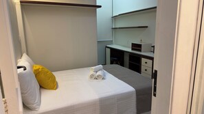 Ein kleines, ordentlich eingerichtetes Schlafzimmer mit Bett, Schreibtisch und Stuhl.