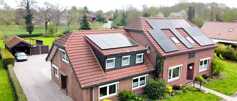 Une maison à deux étages, dotée d’un toit en pente, de panneaux solaires, d’un garage et d’une pelouse bien entretenue.