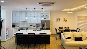 A modern kitchen with white cabinets, a central island with chairs, a dining area with a table and chairs, and a living room with a sofa and a coffee table. - Cozy 2-bedroom, 3 Double queen bed, 2.5 Bath house in San Pedro Sula with AC (San Pedro Sula)