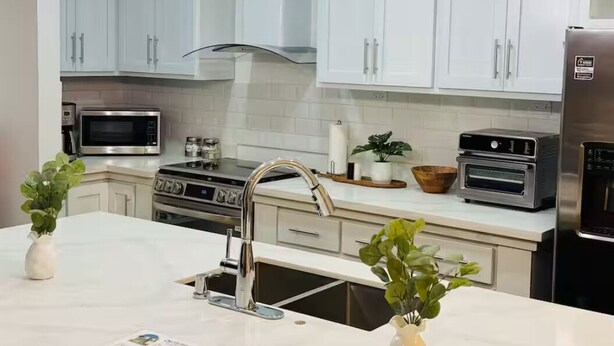 A modern kitchen with white cabinets, stainless steel appliances, and pendant lighting. - Cozy 2-bedroom, 3 Double queen bed, 2.5 Bath house in San Pedro Sula with AC (San Pedro Sula)