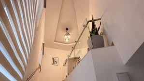 A modern staircase with wooden steps, a glass railing, and a ceiling light fixture. - Cozy 2-bedroom, 3 Double queen bed, 2.5 Bath house in San Pedro Sula with AC (San Pedro Sula)