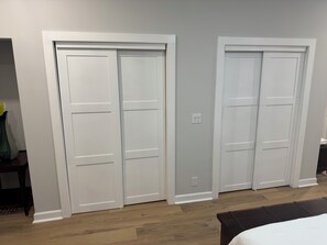 A room with two white doors, a wooden floor, and a bed with a white bedspread. - 3-bedroom house w/ AC in charming Atlanta, close to stadium - newly renovated (Atlanta)