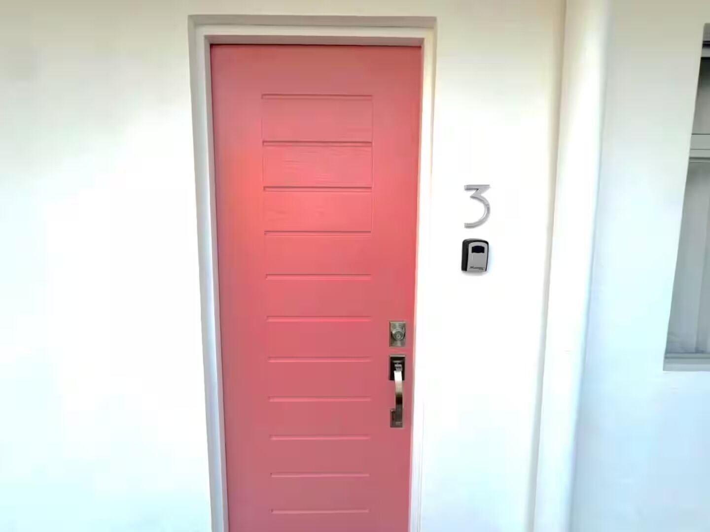 A red door with a keypad lock, a number '3' above it, and a small window to the right.