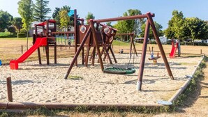 A playground with swings, a slide, and a climbing structure. - Comfort Mobile Home by Sea for 6 (Brtonigla)