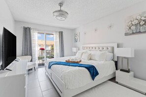 Un dormitorio moderno con una cama grande, un escritorio, un televisor y un balcón con vistas.