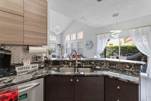 Una cocina con barra de café, fregadero y lavavajillas.