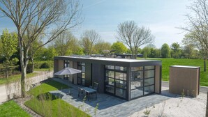 A modern building with a patio area, large windows, and a flat roof. - Lakeside Villa With Finnish Sauna (Workum)