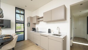 A modern kitchen with a built-in oven, a sink, and a dining area with a table and chairs. - Lakeside Villa With Finnish Sauna (Workum)
