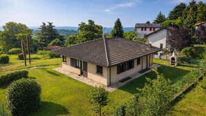 A single-story house with a tiled roof, surrounded by a well-maintained lawn and trees.