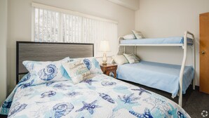 A bedroom with a bed, a nightstand, a lamp, a window with blinds, and a bunk bed. - 3 Bedroom Penthouse (Port Clinton)