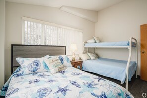 A bedroom with a bed, a nightstand, a lamp, a window with blinds, and a bunk bed. - 3 Bedroom Penthouse (Port Clinton)