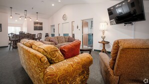 A spacious living room with a large flat-screen TV, patterned sofas, a dining area with wooden furniture, and pendant lighting. - 3 Bedroom Penthouse (Port Clinton)