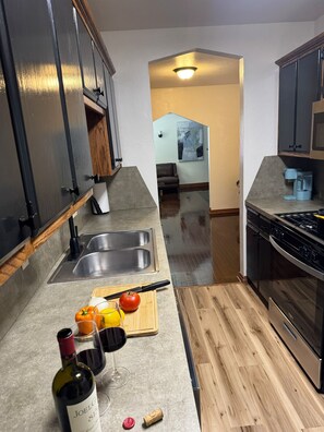 Una cocina con un lavamanos doble, encimera de madera y vista a otra habitación.