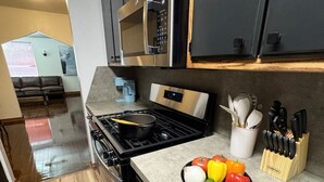 Een moderne keuken met een roestvrijstalen fornuis, zwarte kastjes en een aanrecht met een messenblok.