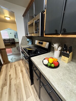 Una cocina moderna con estufa de acero inoxidable, gabinetes negros y una encimera con un bloque de cuchillos.