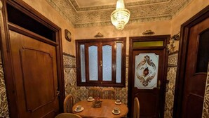 A dining area with a wooden table, chairs, and a chandelier. - A comfortable family apartment in tangier. (Tanger)