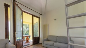 Un salon comprenant un canapé, un fauteuil, une porte-fenêtre coulissante et un radiateur.