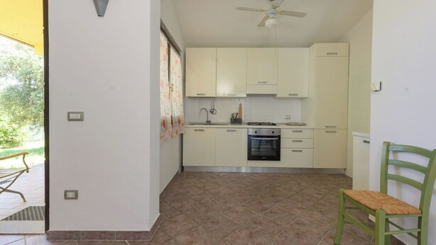 Une cuisine avec des meubles blancs, une cuisinière à gaz, un four encastré et un ventilateur de plafond.