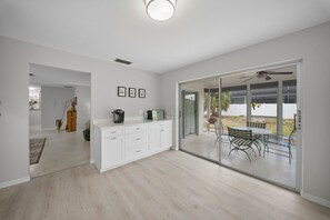 Eine moderne Küche mit weißen Schränken, ein Essbereich mit Tisch und Stühlen sowie eine Glastür, die auf eine Terrasse im Freien führt.