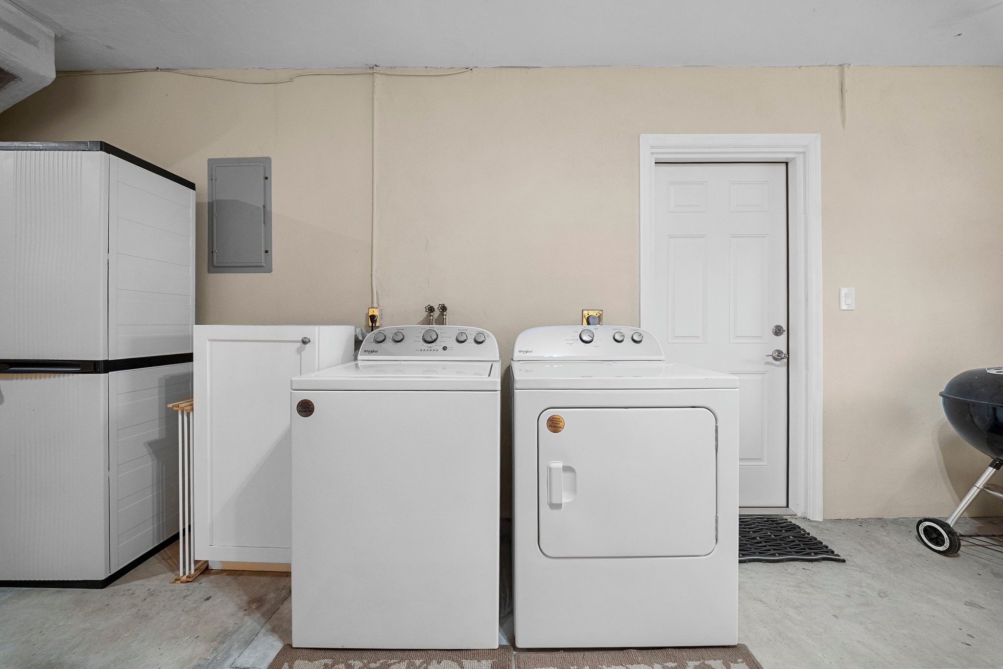 Un lavadero con dos lavadoras y una secadora, un refrigerador blanco y una puerta.