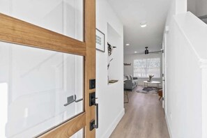 A hallway with a wooden door, a white wall, and a ceiling fan. - Charming Urban Home with pet friendly backyard (Austin)