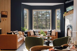 Un salon moderne avec un canapé en cuir, des fauteuils verts et une cheminée.