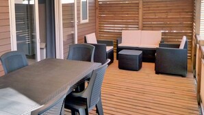Una veranda esterna con tavolo e sedie, un divano e un pontile in legno.