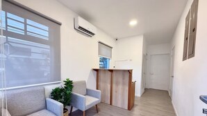 Un espace d’attente moderne, comprenant un canapé, une petite table et une plante.