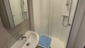 A bathroom with a glass-enclosed shower, a sink, and a mirror. - Golden Palm Resort - Palm Skye PG155 (Chapel Saint Leonards)