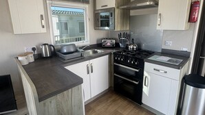 A compact kitchen with a stove, oven, microwave, and sink. - Golden Palm Resort - Palm Skye PG155 (Chapel Saint Leonards)