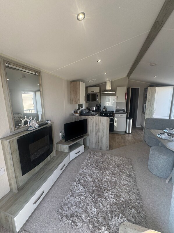 A modern kitchen with a flat-screen TV, wooden cabinets, and a stainless steel refrigerator.