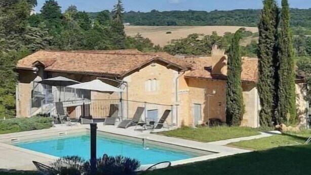Une villa dotée d’une piscine, d’un patio couvert et offrant une vue sur la campagne.