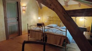 Une chambre à coucher avec un lit, une table de chevet, une lampe et une poutre en bois au plafond.