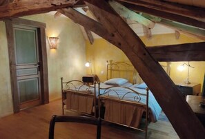 Ein Schlafzimmer mit Bett, Nachttisch, Lampe und Holzbalkendecke.