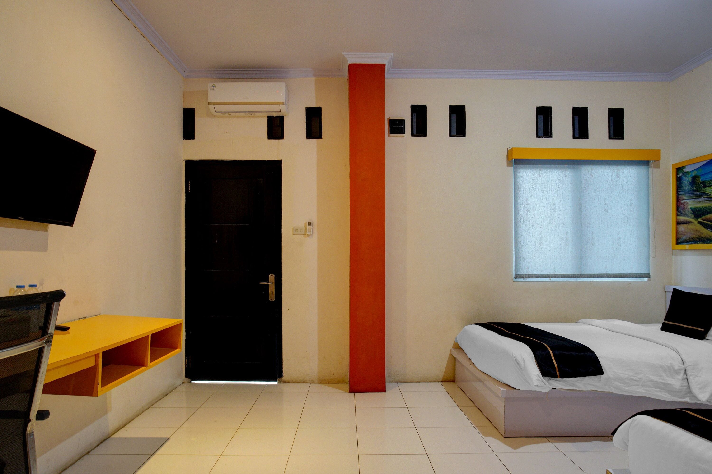 Ein Hotelzimmer mit Bett, Fernseher, Schreibtisch und Fenster.