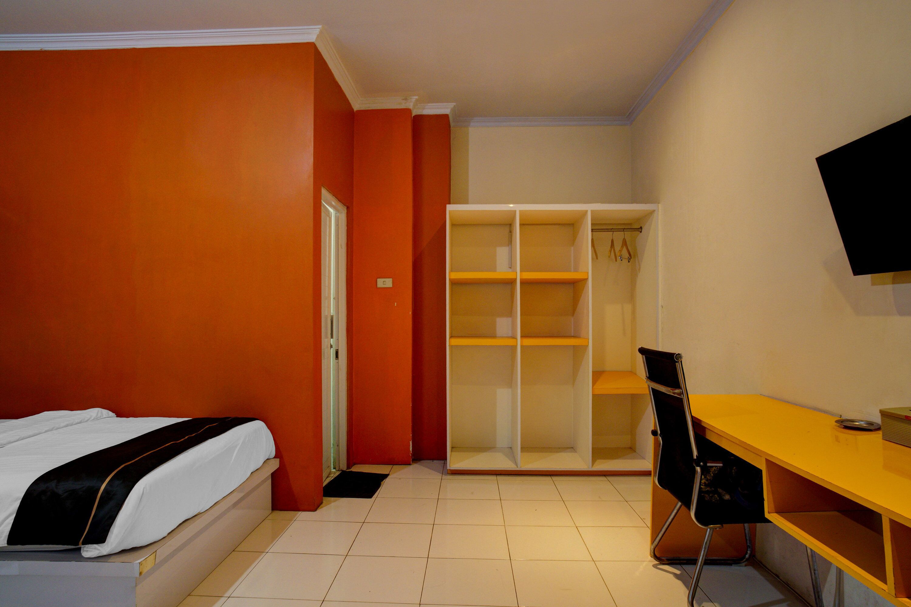 Un dormitorio con cama, escritorio, silla, armario y televisor.