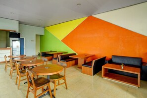 Un interior moderno con mesas y sillas redondas, un sofá y una zona de cocina.