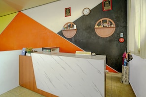 Un mostrador de recepción con encimera de mármol, un reloj y dos estantes adosados a la pared con objetos decorativos.