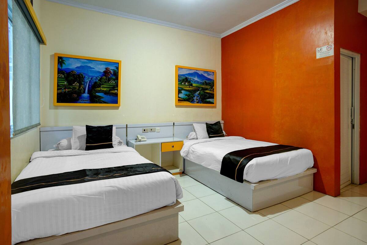 Habitación de hotel con dos camas, un escritorio y dos cuadros en la pared.