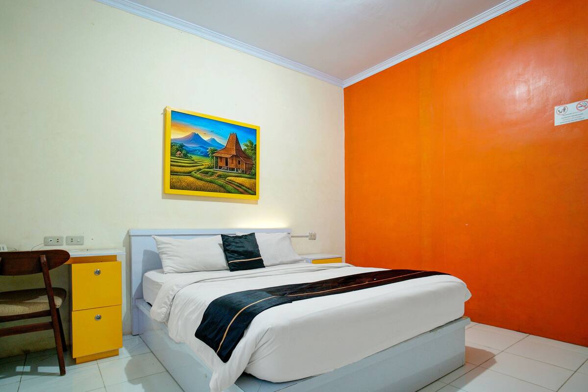 Un dormitorio con cama, escritorio, silla y un cuadro en la pared.