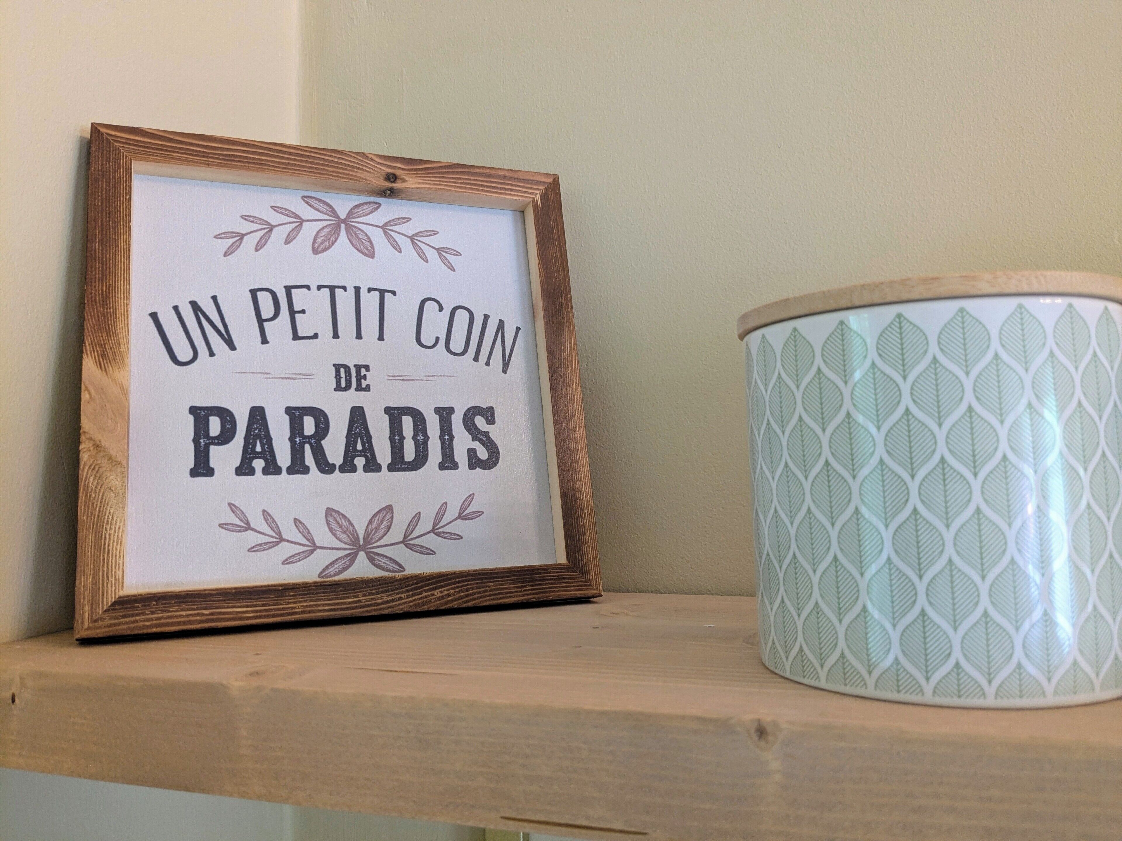 A framed sign with text and a patterned container on a shelf.