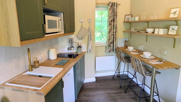 A compact kitchen with a microwave, sink, and a dining area with chairs and a table.