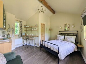 A bedroom with a bed, a desk with chairs, and a kitchenette. - Romantic hideaway in Jumilhac: The Nest, a riverside gem near the château (Jumilhac-le-Grand)