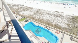 Una piscina dal design circolare, una spiaggia con ombrelloni e vista sull'oceano.