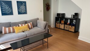 Ein Wohnzimmer mit grauem Sofa, einem schwarzen Couchtisch und einer schwarzen TV-Konsole mit Stauraumkörben.