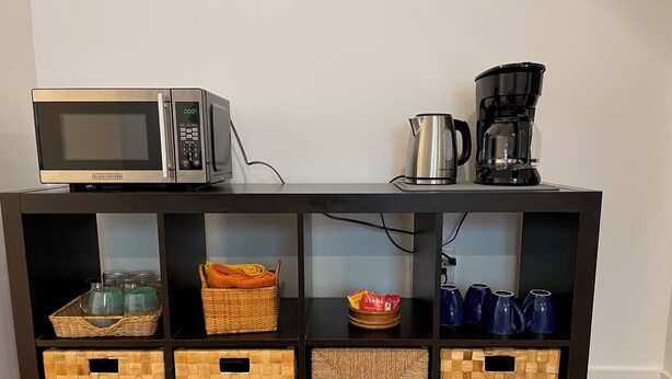 Eine Küchenarbeitsplatte mit einer Mikrowelle, einer Kaffeemaschine und Aufbewahrungskörben.