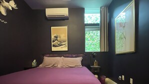 Een slaapkamer met een bed, een raam en kunst aan de wanden.